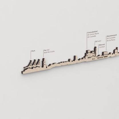 Primer plano de El Fadrí en la silueta del skyline de Castelló en madera natural.