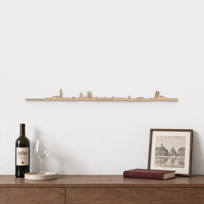 Skyline de Burdeos de 100 cm en madera con acabado marrón, sobre aparador con vino, copa y lámina de arquitectura francesa.