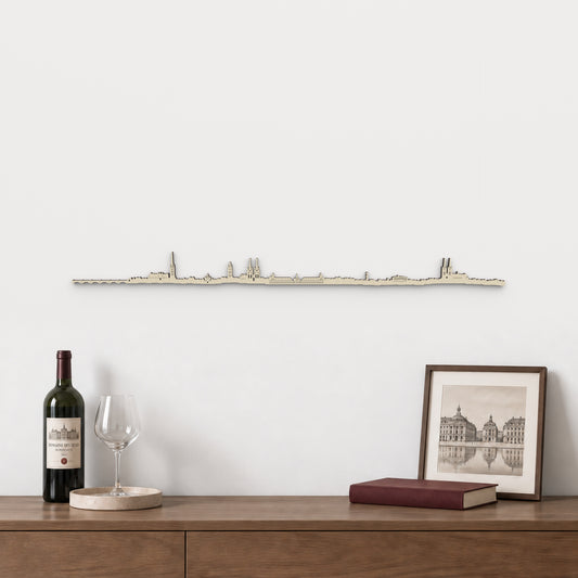 Skyline de Burdeos de 100 cm en madera natural, sobre aparador con vino, copa y lámina de arquitectura francesa.
