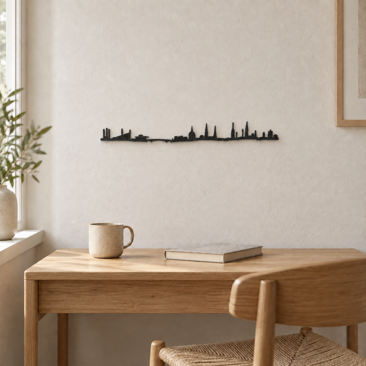 Skyline de Copenhague en madera negra sobre un escritorio de madera clara con una taza y un libro.
