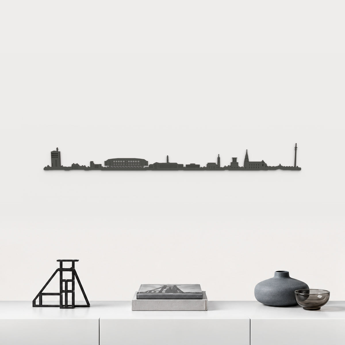 Skyline von Gelsenkirchen mit schwarzem Finish, 100 cm, über dem weißen Möbelstück mit Stahl, Büchern und blaugrauer Keramik, in einer von der Stadt inspirierten Einrichtung.