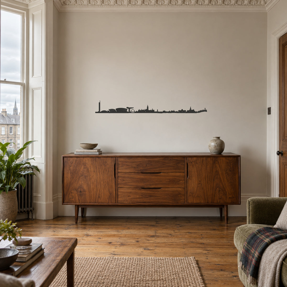 Skyline de Glasgow de 100 cm en madera negra sobre un aparador de nogal, en un salón de inspiración escocesa con molduras, ventanal y manta de tartán.
