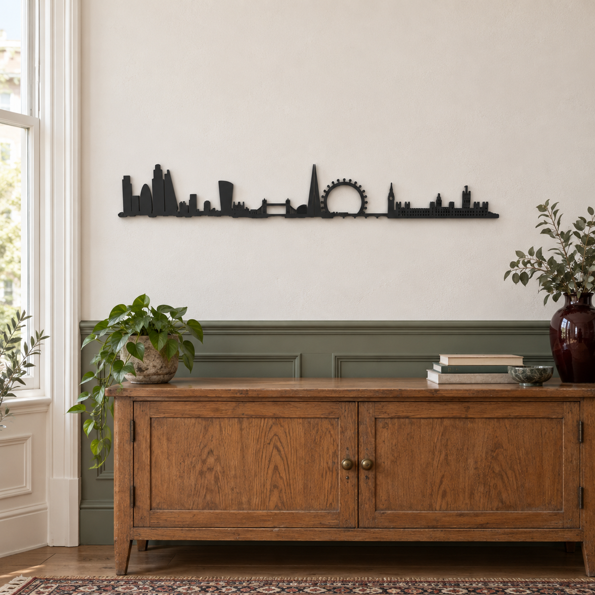 Skyline de Londres en madera negra sobre un aparador de madera, con molduras verdes y plantas.