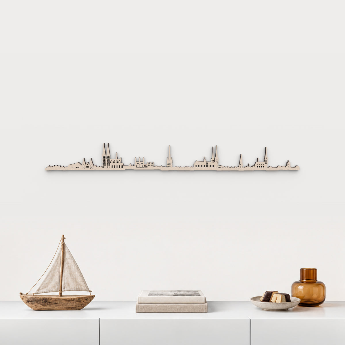 Skyline de Lübeck en madera natural sobre un mueble blanco, con decoración inspirada en la ciudad.