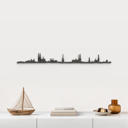 Skyline de Lübeck en acabado negro, presentado sobre el mueble blanco con velero de madera, libros, mazapán y vidrio ámbar, en una decoración inspirada en la ciudad.