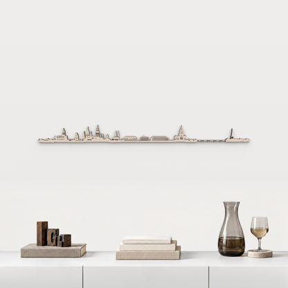 Skyline de Mainz en acabado natural, presentado sobre el mueble blanco con tipos de imprenta, libros, decantador y copa de vino, en una decoración inspirada en la ciudad.