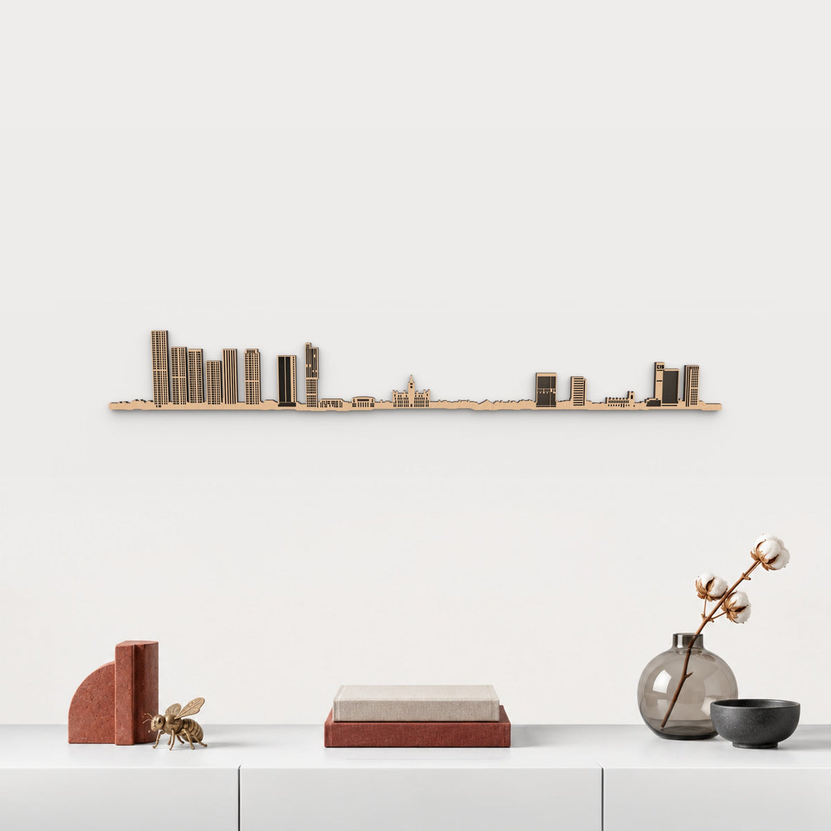 Skyline de Manchester en acabado marrón, presentado sobre el mueble blanco con libros, cerámica y una abeja de latón inspirada en Manchester, en una decoración inspirada en la ciudad.