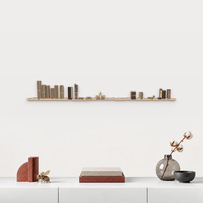 Skyline de Manchester en acabado marrón, presentado sobre el mueble blanco con libros, cerámica y una abeja de latón inspirada en Manchester, en una decoración inspirada en la ciudad.