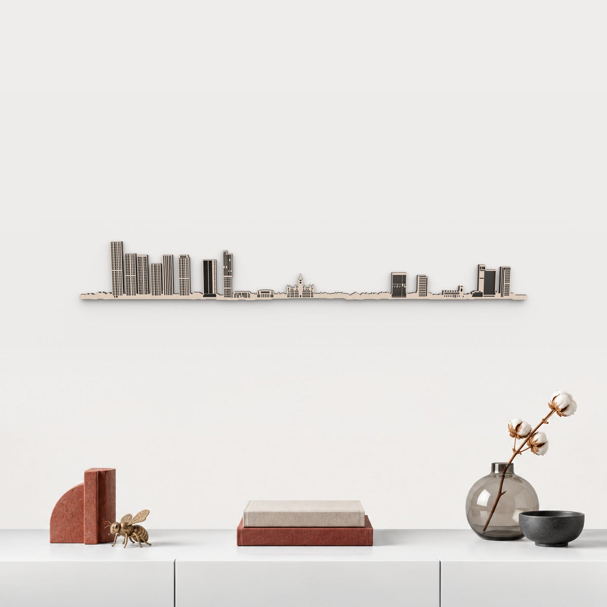 Skyline de Manchester en acabado natural, presentado sobre el mueble blanco con libros, cerámica y una abeja de latón inspirada en Manchester, en una decoración inspirada en la ciudad.