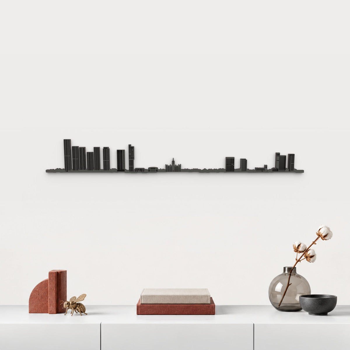 Skyline de Manchester en acabado negro, presentado sobre el mueble blanco con libros, cerámica y una abeja de latón inspirada en Manchester, en una decoración inspirada en la ciudad.
