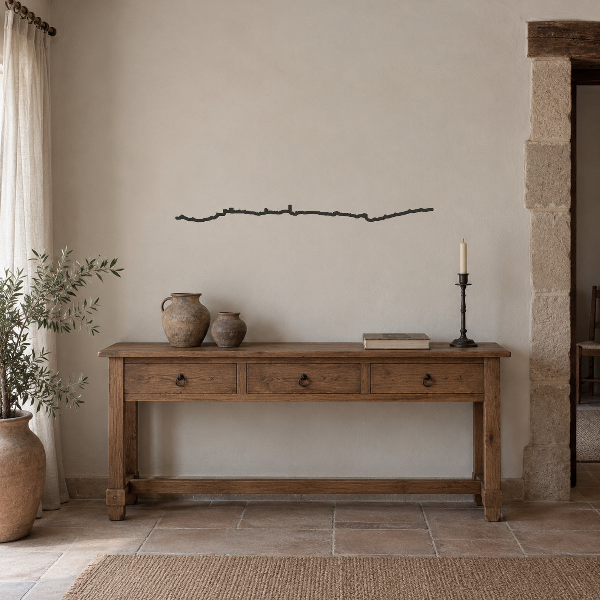 Skyline de Pedraza negro de 100 cm en un hogar castellano, sobre consola de madera con cerámica y candelero.