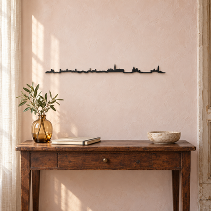 Skyline de Venecia en madera negra sobre una consola antigua, con jarrón ámbar y pared rosada.