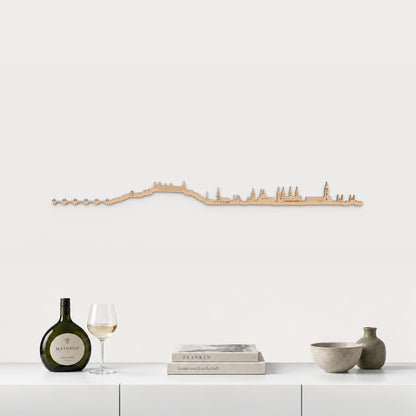 Skyline von Würzburg mit braunem Finish, 100 cm, über dem weißen Möbelstück mit fränkischem Wein, Büchern und Keramik, in einer von der Stadt inspirierten Einrichtung.