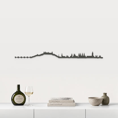 Skyline von Würzburg mit schwarzem Finish, 100 cm, über dem weißen Möbelstück mit fränkischem Wein, Büchern und Keramik, in einer von der Stadt inspirierten Einrichtung.